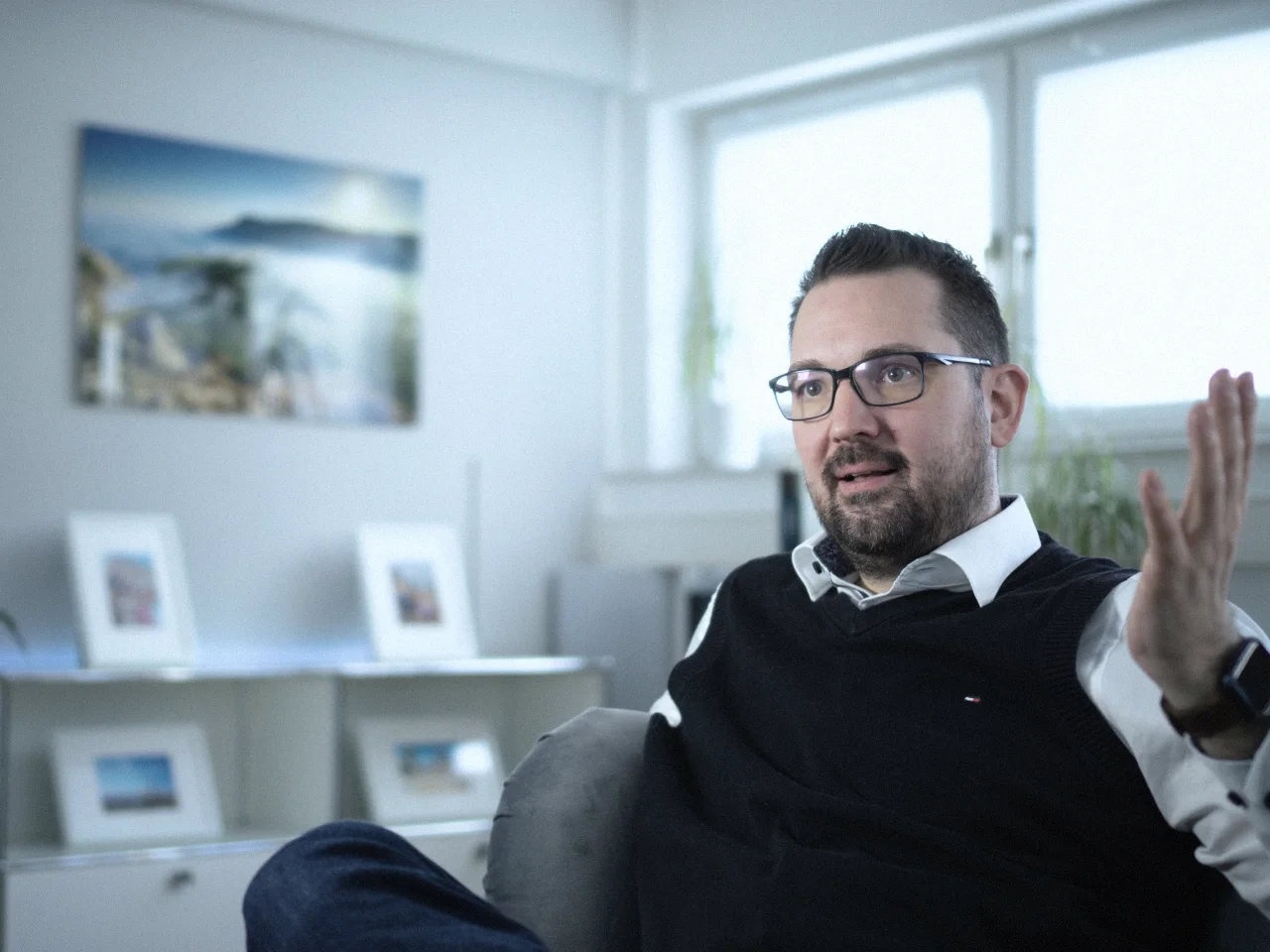 Robin Steinheimer sitzt im Büro im Sessel und erklärt etwas mit offener Hand